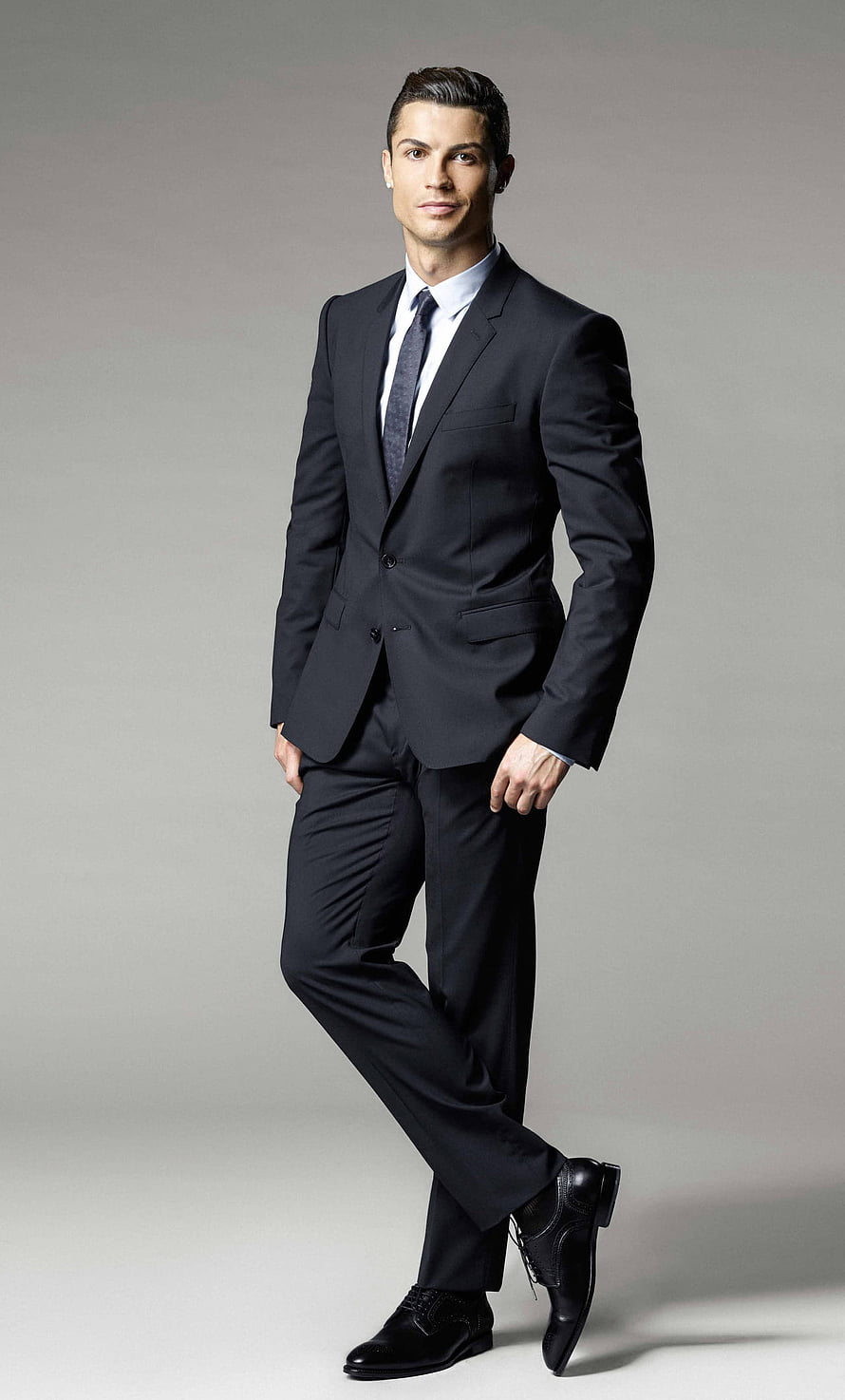 Cristiano Ronaldo in a tailored black suit and dress shoes for a professional studio portrait HD phone wallpaper