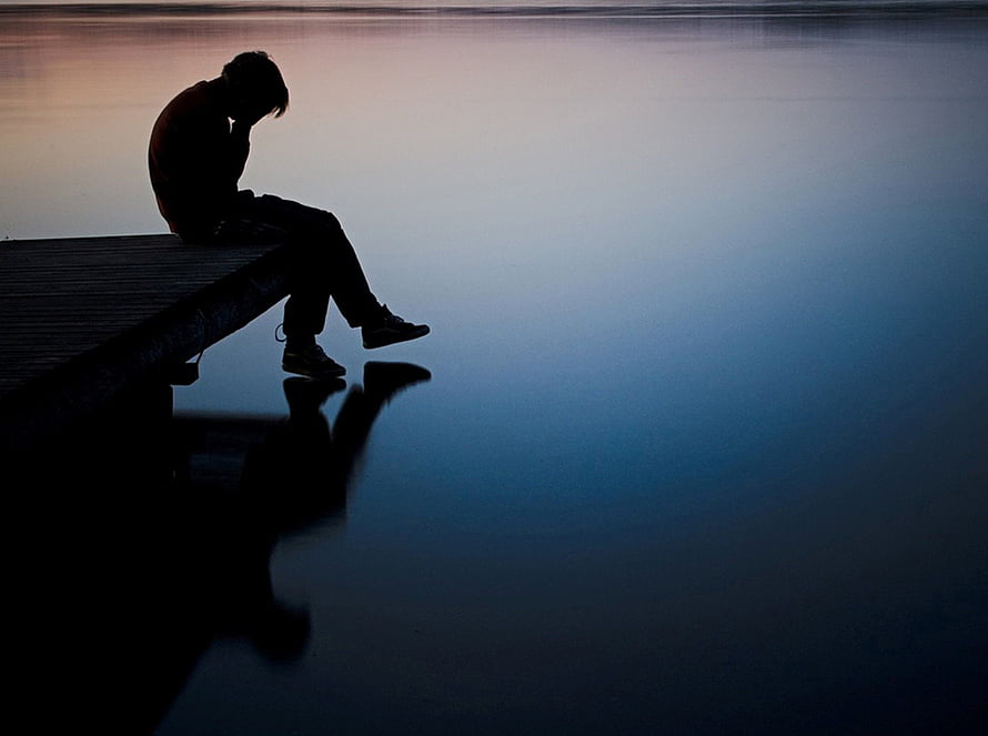 Silhouette of a solitary figure sitting on a dock at dusk with a calm water reflection HD wallpaper