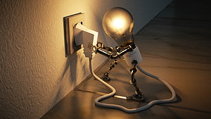 Glowing Light Bulb Robot Plugging Into Wall Outlet in Warm Interior Setting HD wallpaper