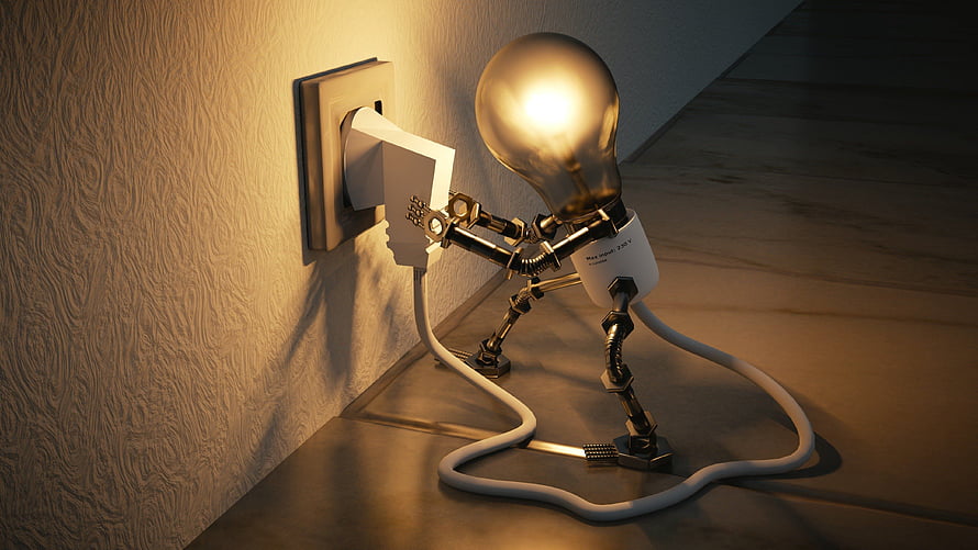 Glowing Light Bulb Robot Plugging Into Wall Outlet in Warm Interior Setting HD wallpaper
