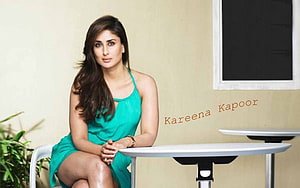 Kareena Kapoor in a teal sleeveless dress seated at a modern table HD wallpaper