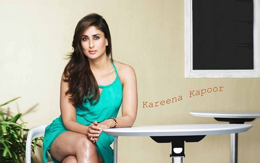Kareena Kapoor in a teal sleeveless dress seated at a modern table HD wallpaper