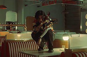 DPR Ian in a moody retro diner scene holding a pistol with cinematic lighting HD wallpaper