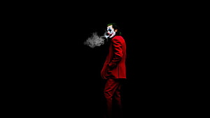 Joker in red suit smoking against a dark background HD wallpaper