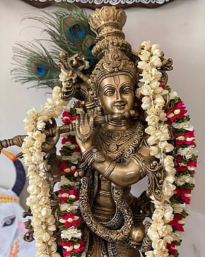 Ornate Brass Krishna Statue Playing Flute with Peacock Feather and Floral Garland HD phone wallpaper