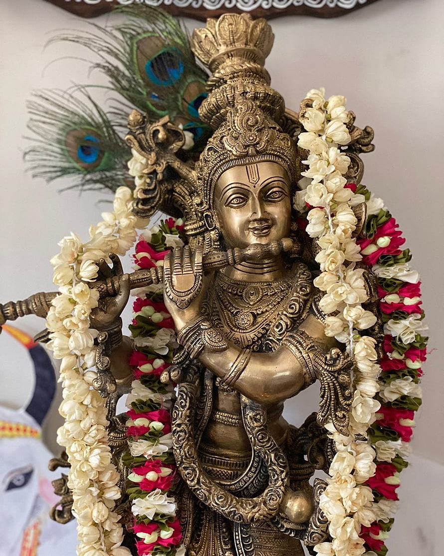 Ornate Brass Krishna Statue Playing Flute with Peacock Feather and Floral Garland HD phone wallpaper