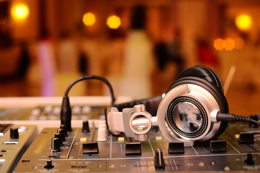 Professional DJ Headphones Resting on Audio Mixer Console in Warm Club Setting HD wallpaper