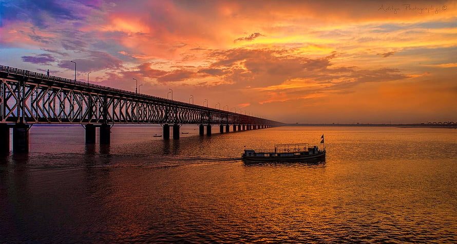 Long steel truss bridge and small boat on the Godavari River at sunset in Rajahmundry HD wallpaper