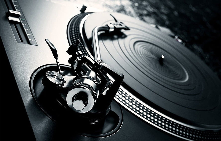 Close-up of a professional DJ turntable with vinyl record and tonearm in monochrome HD wallpaper