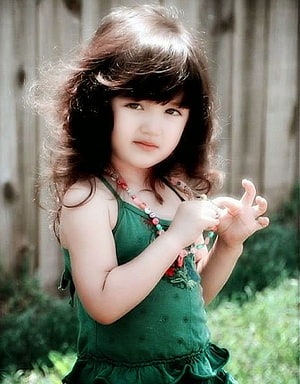 Young Girl in Green Dress with Beaded Necklace and Curly Hair HD phone wallpaper