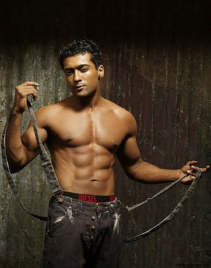 Surya shirtless studio portrait with suspenders and dark jeans against a textured wall HD phone wallpaper