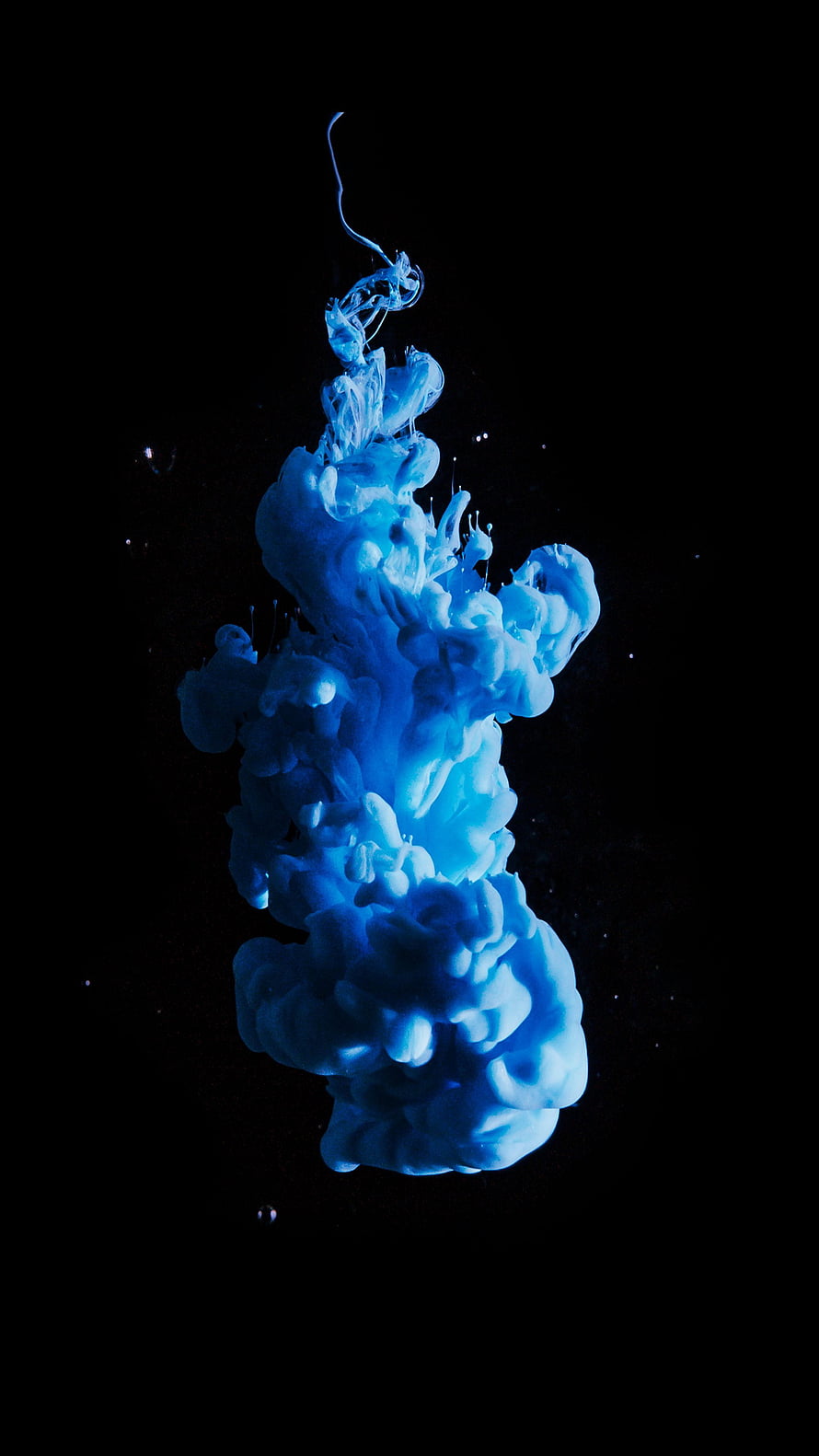 Vibrant Blue Ink Diffusing in Water Against a Deep Black Background HD phone wallpaper
