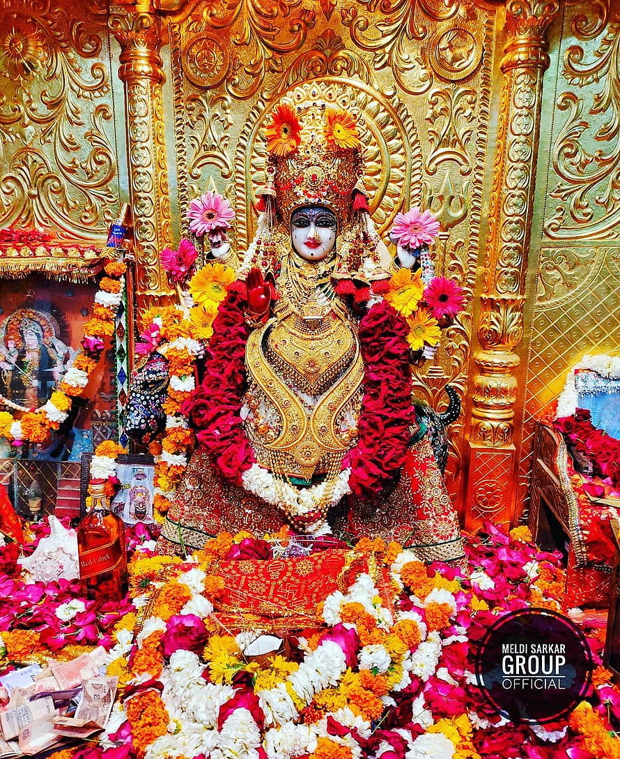 Meldi Sarkar Maa adorned in gold jewelry and vibrant flower garlands at a temple shrine HD phone wallpaper