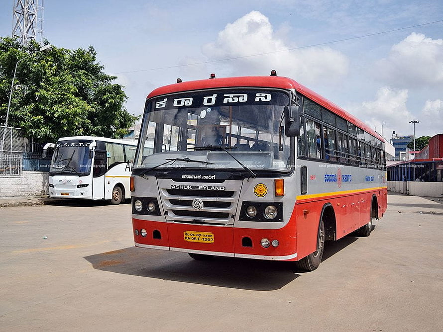 KSRTC Ashok Leyland red and silver intercity bus parked at a transit depot under a bright sky HD wallpaper