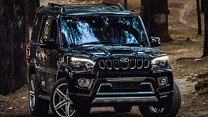 Black Mahindra Scorpio S11 SUV parked on a forest trail with rugged off-road styling HD wallpaper
