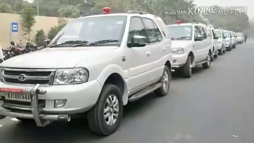 White Mahindra Scorpio SUV Convoy with Red Roof Beacons on City Road HD wallpaper