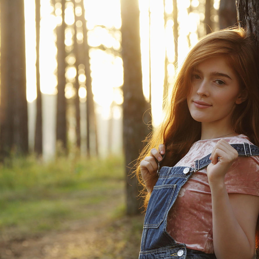 Jia Lissa in Denim Overalls and Pink Top Leaning Against a Tree in a Sunlit Forest HD phone wallpaper