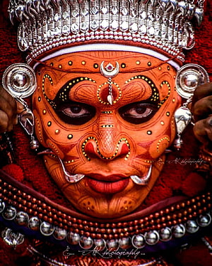 Close-up portrait of a Theyyam performer in traditional Kerala ritual makeup and silver headdress HD phone wallpaper