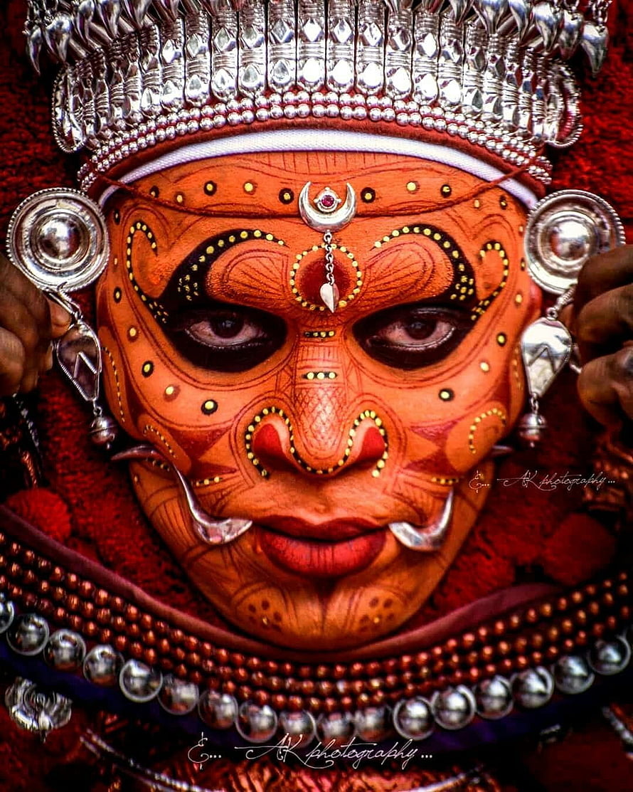 Close-up portrait of a Theyyam performer in traditional Kerala ritual makeup and silver headdress HD phone wallpaper