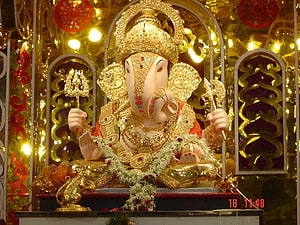 Ganpati Bappa Murti Adorned in Gold Jewelry and Floral Garland HD wallpaper