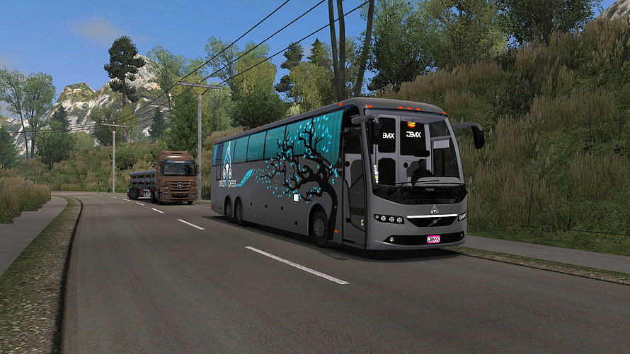 Grey Touring Bus with Cyan Tree Decal Driving on Mountain Road HD wallpaper