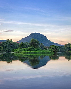 Serene Lake Reflection of a Lush Green Hill at Golden Hour HD phone wallpaper