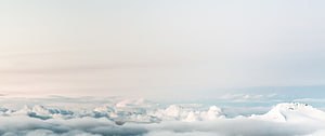 Serene Snow-Capped Mountain Peak Rising Above a Vast Sea of Clouds in Soft Pastel Light HD wallpaper