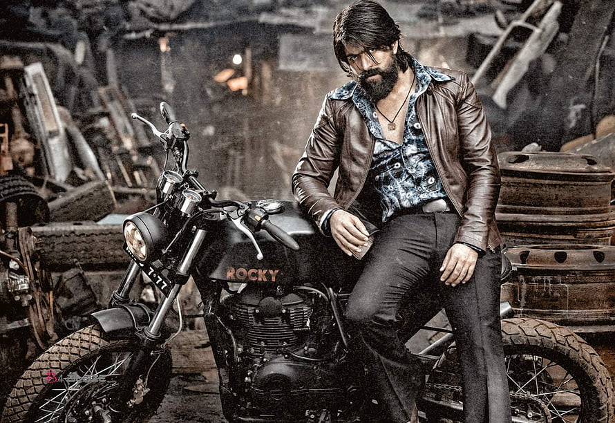 Yash as Rocky in KGF Chapter 2 promotional still on a vintage motorcycle in a gritty scrapyard setting HD wallpaper