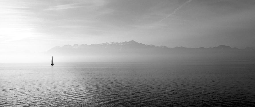 Monochrome Sailboat on Calm Waters with Distant Mountain Range HD wallpaper