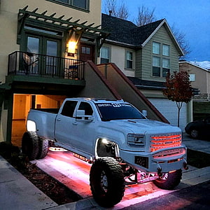 White Lifted GMC Sierra 2500HD with Underglow Lighting Parked in a Residential Driveway at Dusk HD phone wallpaper