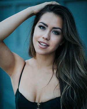 Alina Lopez Portrait With Long Wavy Hair And Black Top Against Teal Background HD phone wallpaper
