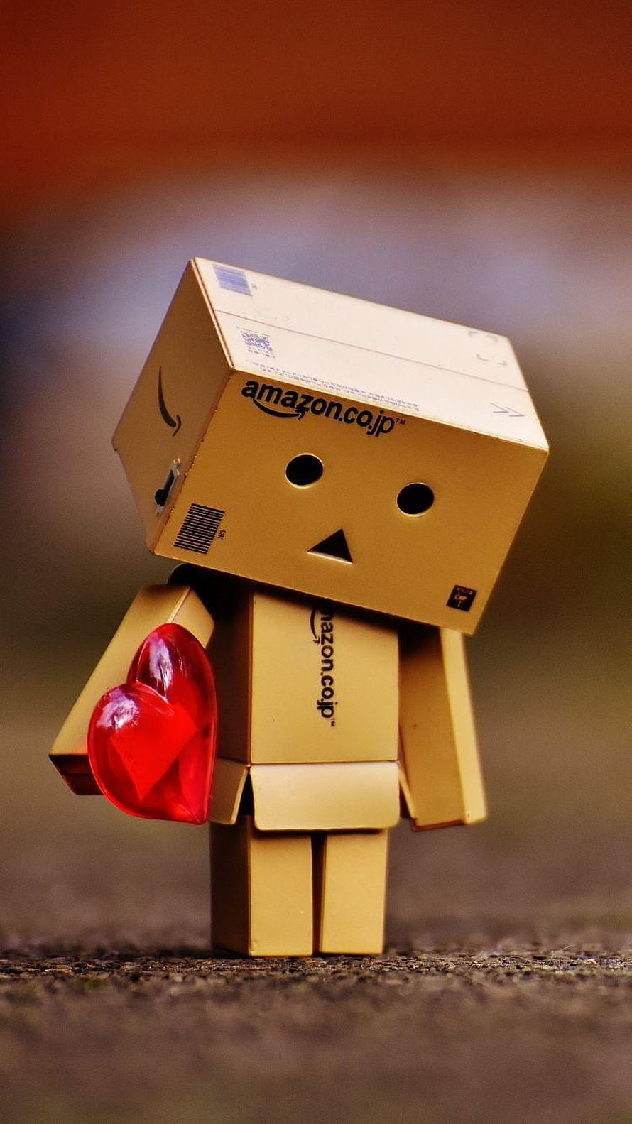 Danbo cardboard robot holding a red heart with Amazon branding on a warm background HD phone wallpaper