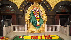 Sai Baba Temple Statue Adorned With Marigold Garlands and Green Robe HD wallpaper