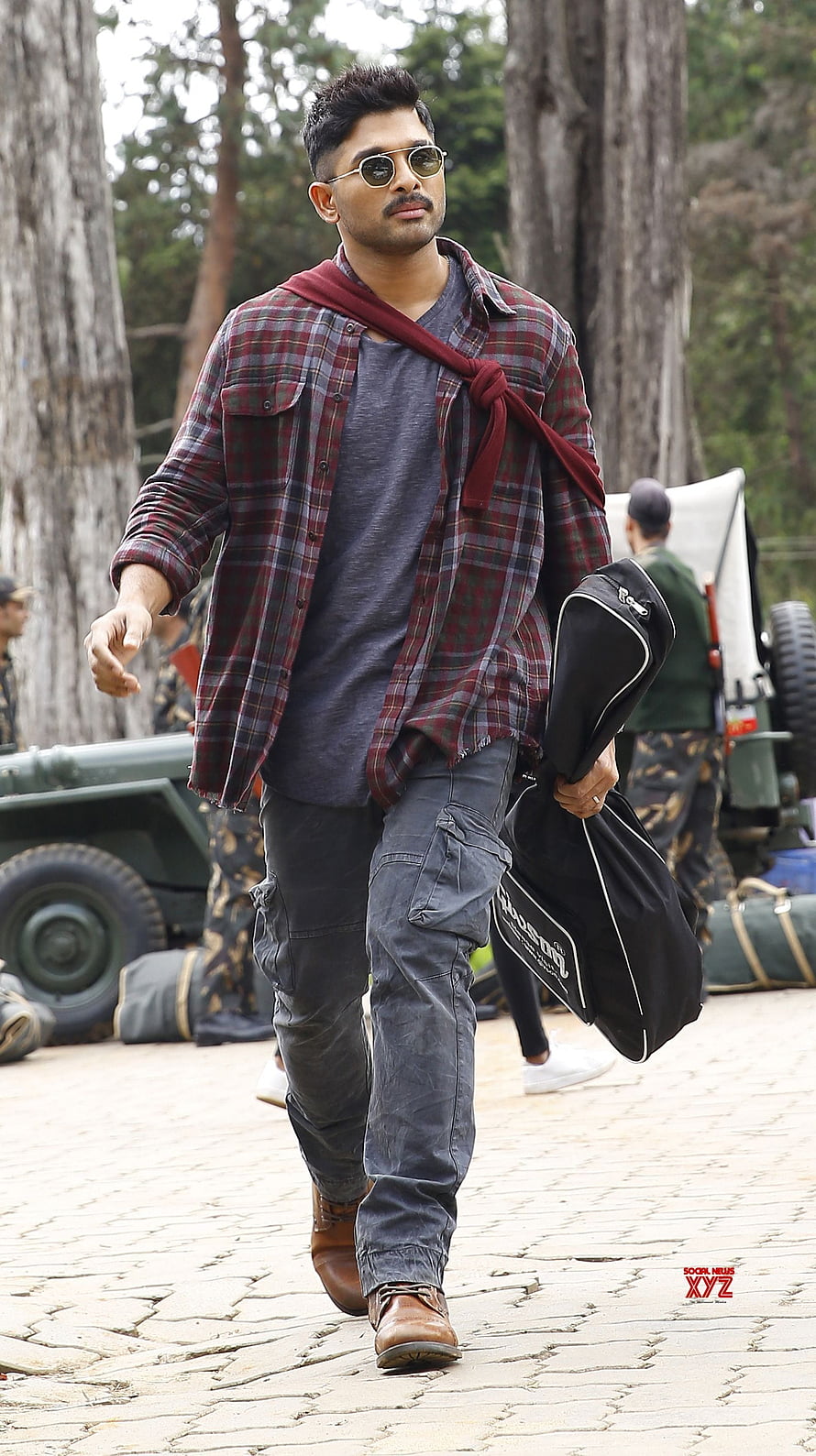 Allu Arjun in rugged plaid shirt and cargo pants on a forest film set HD phone wallpaper