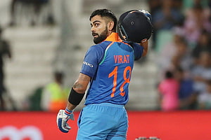 Virat Kohli in Indian cricket jersey holding helmet on the field HD wallpaper