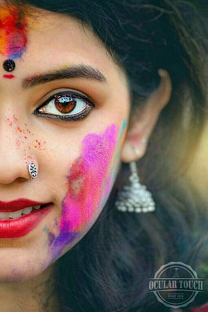 Close-up portrait of a woman with vibrant Holi festival colors on her face HD phone wallpaper