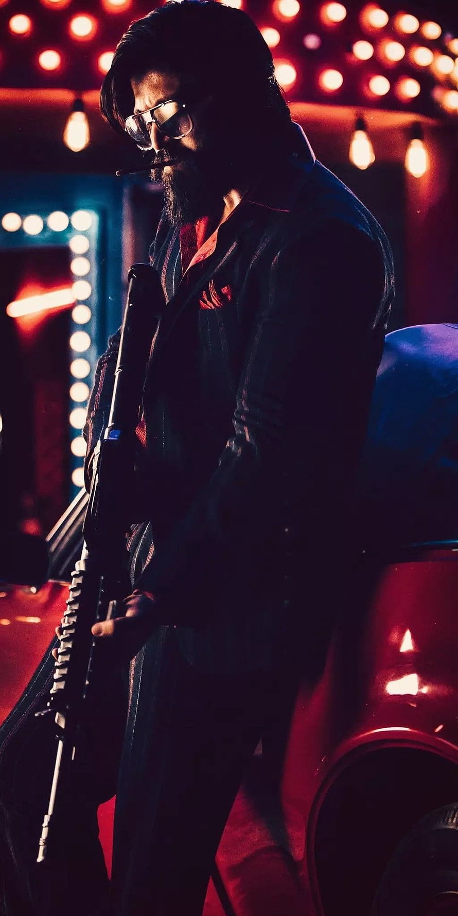 Rocky Bhai from KGF Chapter 1 in a dark suit holding a rifle under red neon lights HD phone wallpaper