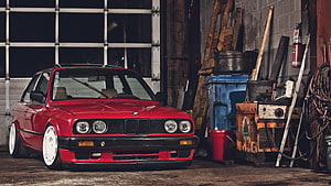 Red BMW E30 Coupe with White Wheels Parked in a Cluttered Garage Workshop HD wallpaper
