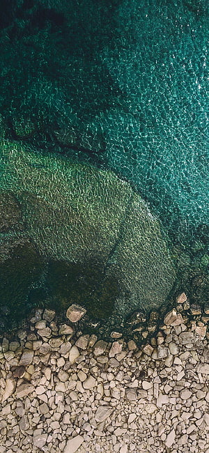 Aerial View of Turquoise Water Meeting a Rocky Shoreline HD phone wallpaper