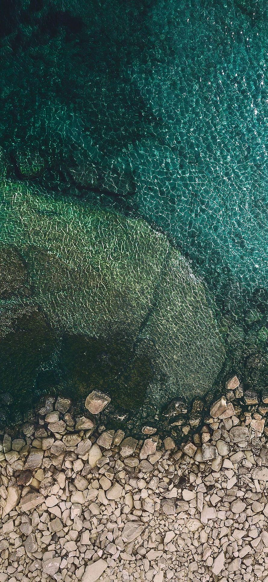 Aerial View of Turquoise Water Meeting a Rocky Shoreline HD phone wallpaper