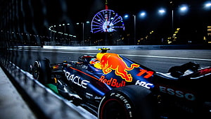 Oracle Red Bull Racing Formula 1 car on the night track with a lit Ferris wheel in the background HD wallpaper