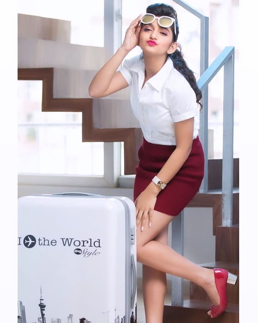 Sreeleela in white shirt and maroon skirt posing with travel suitcase on stairs HD phone wallpaper