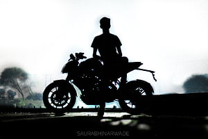Silhouette of a Rider on a Sport Motorcycle Against a Bright Hazy Sky HD wallpaper