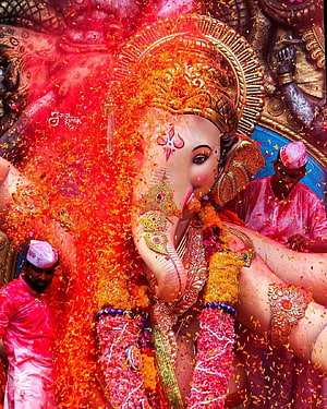 Ganesh Ji adorned in vibrant marigold garlands during a festive Hindu celebration with devotees HD phone wallpaper