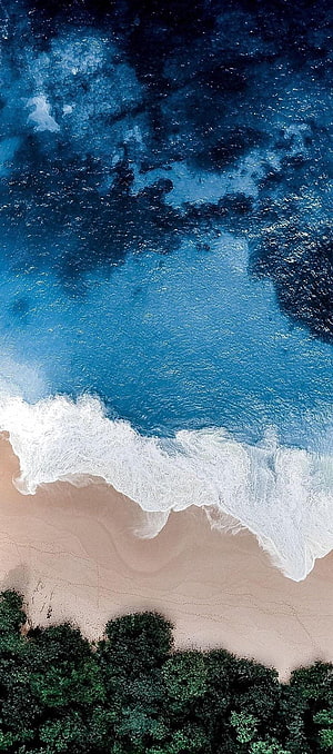 Aerial View of Turquoise Ocean Waves Crashing on Sandy Shore with Lush Green Foliage HD phone wallpaper