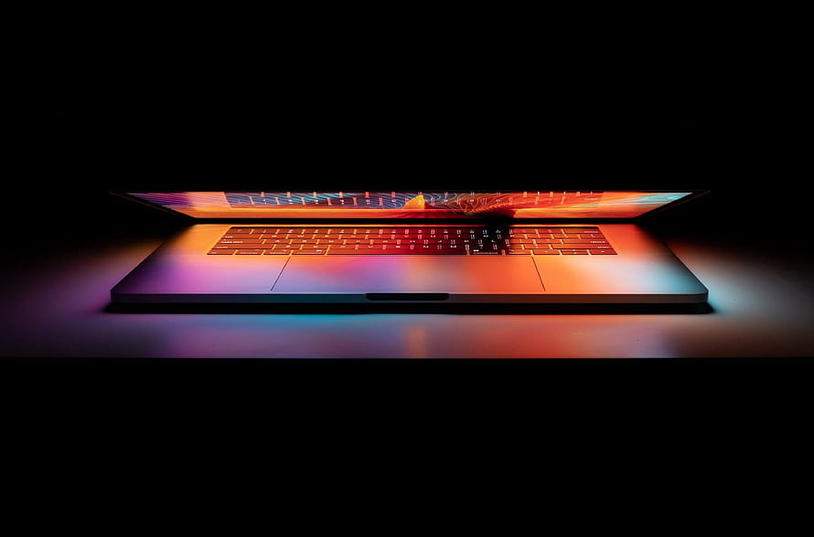Sleek Laptop with Vibrant Backlit Keyboard on Dark Surface HD wallpaper