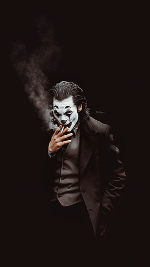 Joker in a dark suit smoking a cigarette with dramatic smoke against a black background HD phone wallpaper