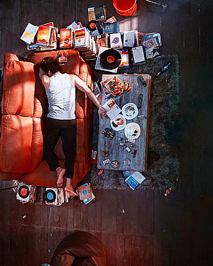 Thalapathy Vijay Reclining on Orange Sofa Amidst Vinyl Records and Books in Master Film Scene HD phone wallpaper