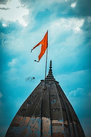 Saffron Bhagwa Flag Flying Above Ancient Temple Spire Against Dramatic Sky HD phone wallpaper