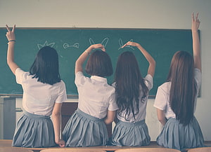 Four Schoolgirls in Uniform Making Peace Signs in Front of a Classroom Blackboard HD wallpaper